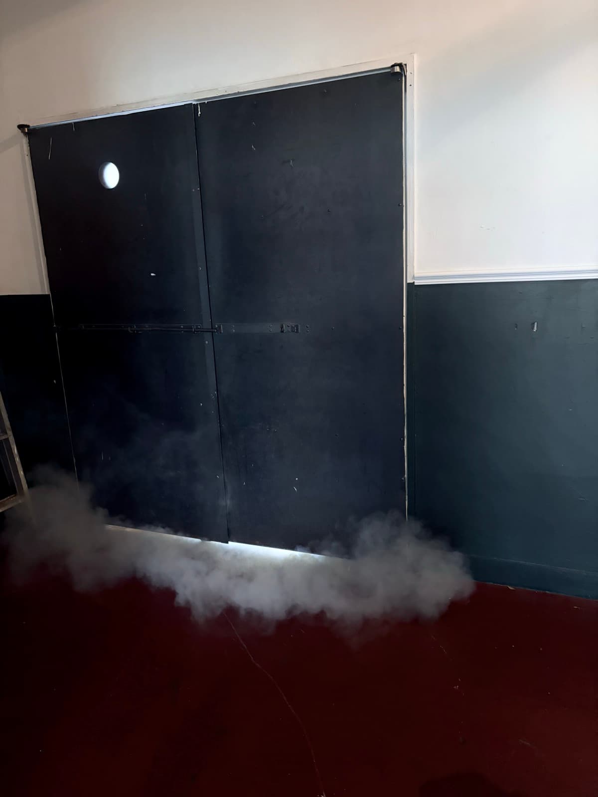 Black double doors of the New Hood venue with fog drifting across the floor