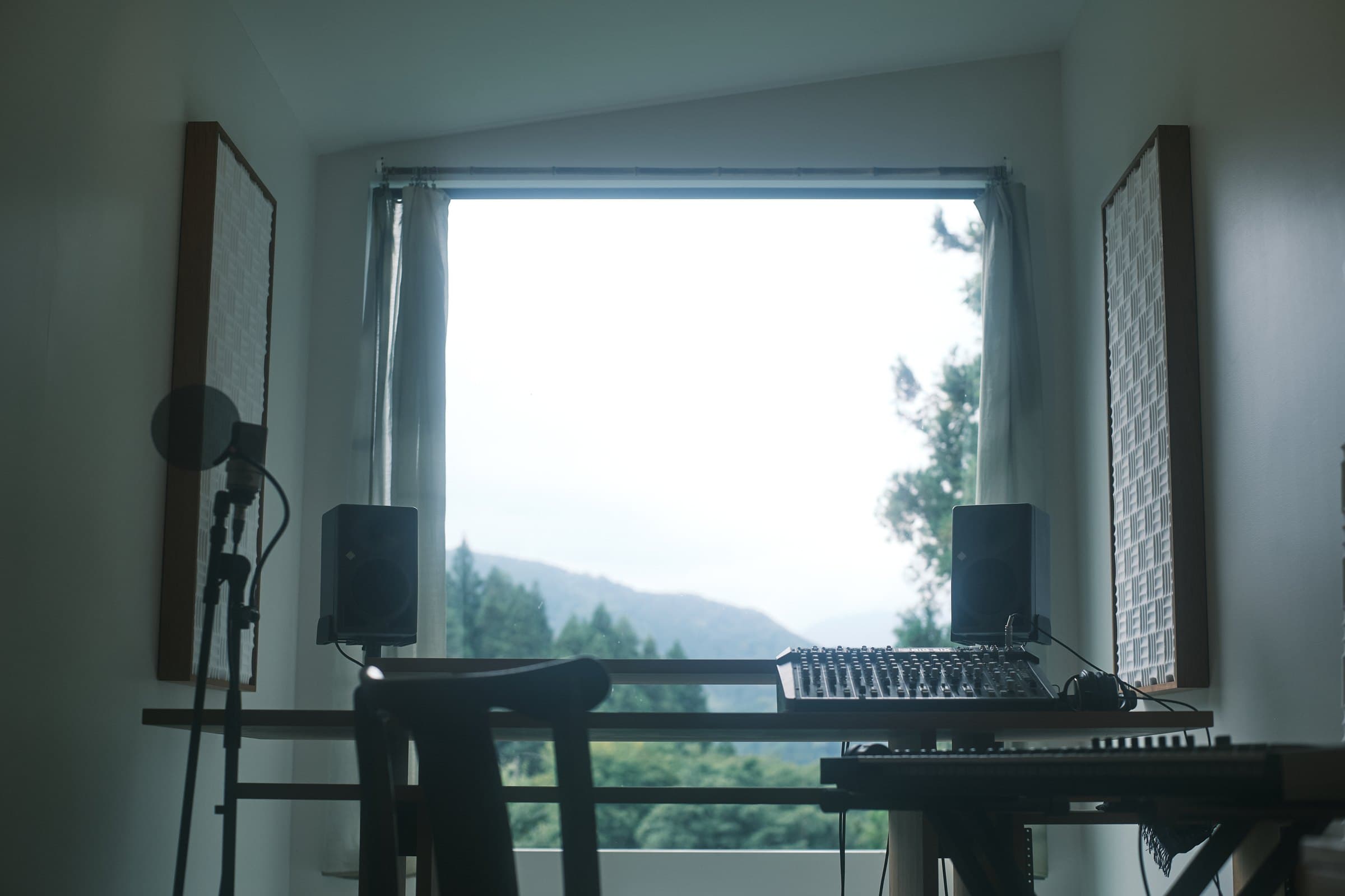 Studio desk at inou studio facing a large window with a mountain view in Fujino