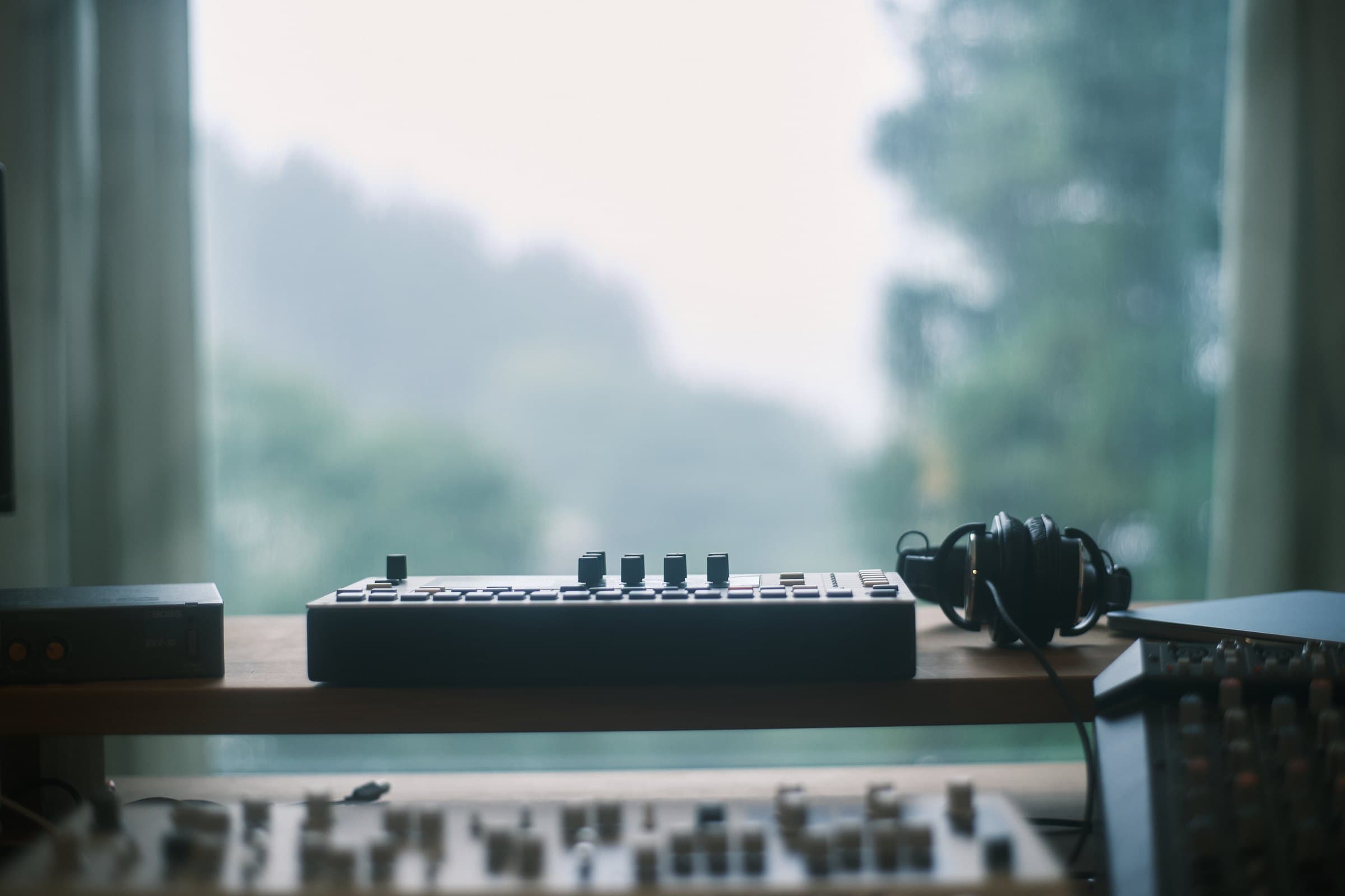 Synthesizer and headphones on the studio desk facing a misty mountain view