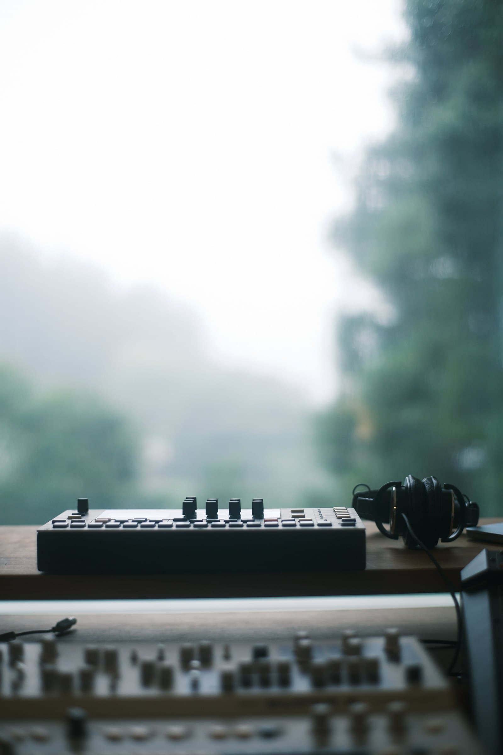 Synthesizer and headphones by the window, overlooking misty mountains in Fujino